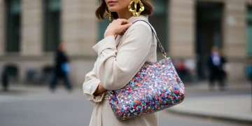 Woman showcasing bold gold earrings and a vibrant sustainable handbag for Spring 2025 fashion